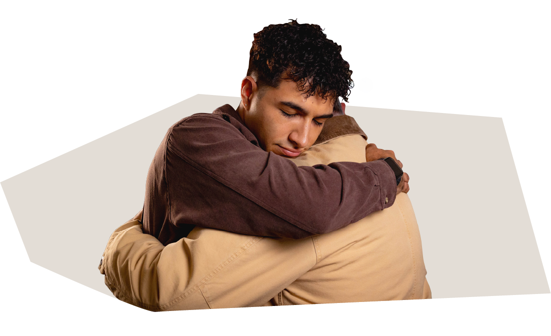 Image of two people hugging over top of a gray shape