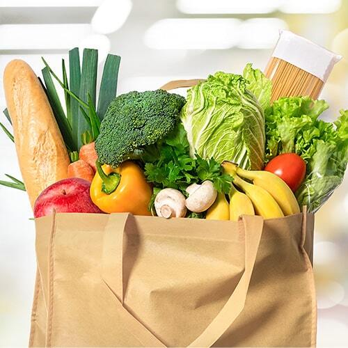 An eco friendly reusable shopping bag filled with vegetables on a blur background.