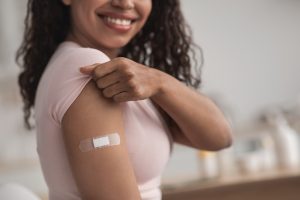 A Female showing her arm with a band-aid after getting vaccination.